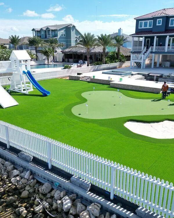 Custom waterfront putting green with artificial grass and a family play area