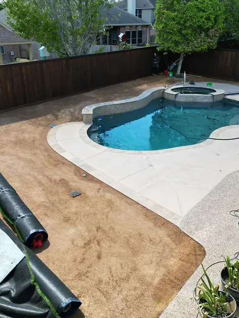 Prepared base and turf rolls during poolside artificial grass installation